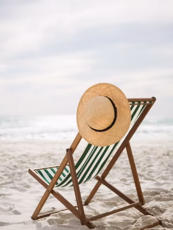 Straw hat kept on empty beach chair at tropical sand beach